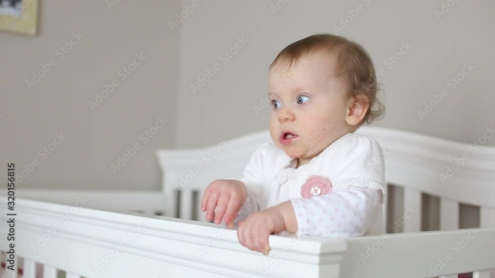 Very Cute 10 Month Old Baby Girl in White Dress playing in White Crib, Happy and Healthy Baby Very Cute 10 Month Old Baby Girl in White Dress playing in White Crib, Happy and Healthy Baby