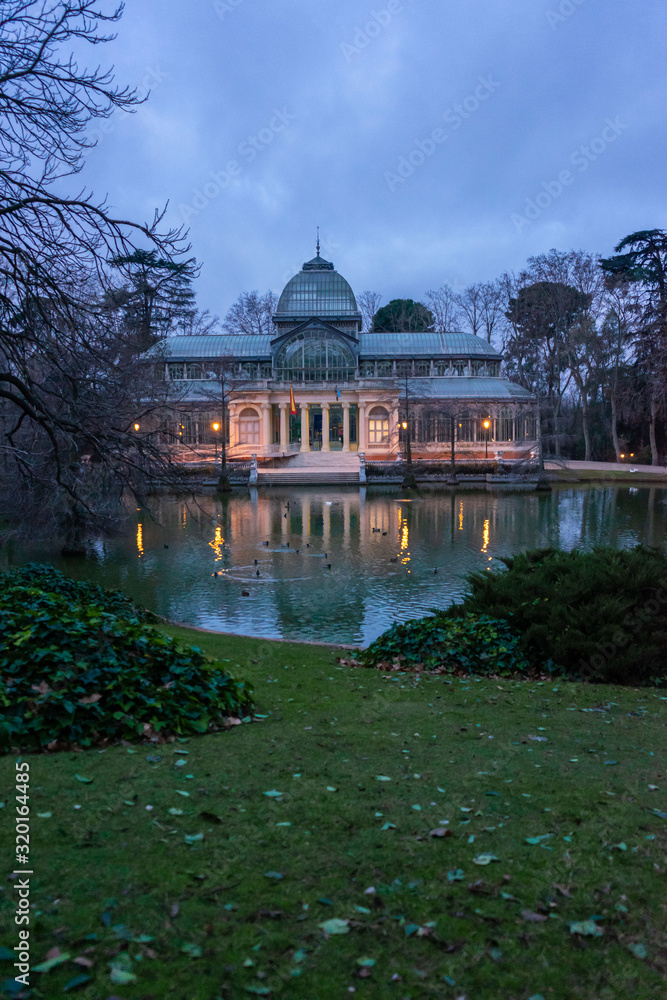 Front view of the lagoon and the Crystal Palace in El Retiro Park in Madrid at dawn, cloudy day, travel concept