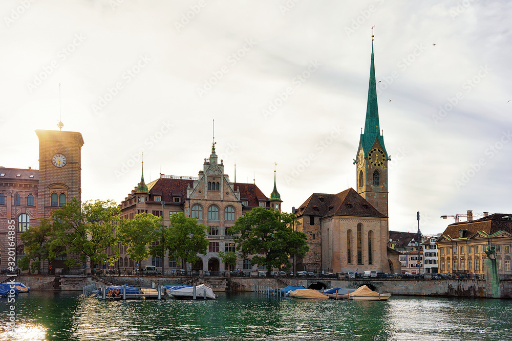 Fraumunster Church and boats Limmat River quay in the city center of Zurich, Switzerland. People on the background