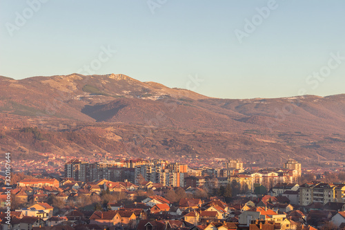 Golden hour view of Pirot cityscape, and impressive, rocky, sunlit summit above the city
