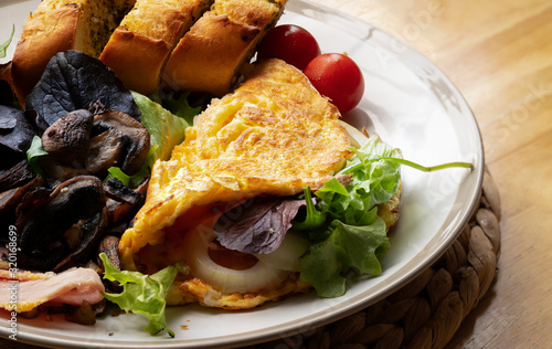 Cropped shop top view Omelette with chees and ham severd with mixed fresh salad, gill mushroom, organic tomato and Garlic bread.Healthy food concept