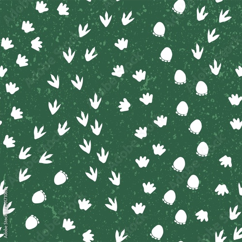 Seamless repeat pattern with different shape white dinosaur foot prints tracks on a green background with a texture