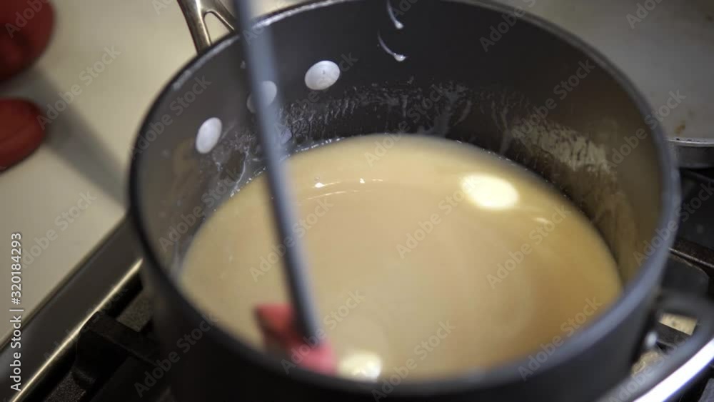 A young girl stirs a caramel mix heating up on the stove while baking millionaire shortbread cookies A young girl stirs a caramel mix heating up on the stove while baking millionaire shortbread cookies