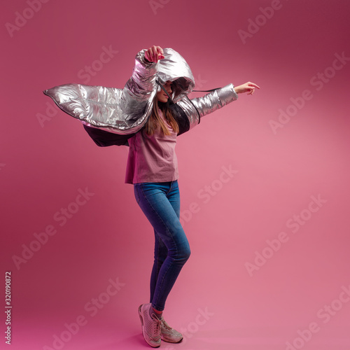 Foto fashionable and modern young woman in a puffy light down jacket throws a hood over her head