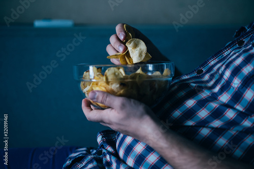 overeating, sedentary lifestyle, bad habits, food addiction, eating disorders. fat overweight man lay on the coach with tv remote and junk food. depression, laziness