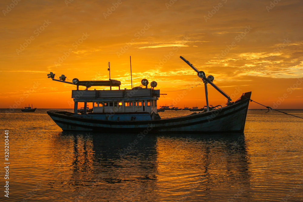 Fishing boat on the background of a golden sunset
