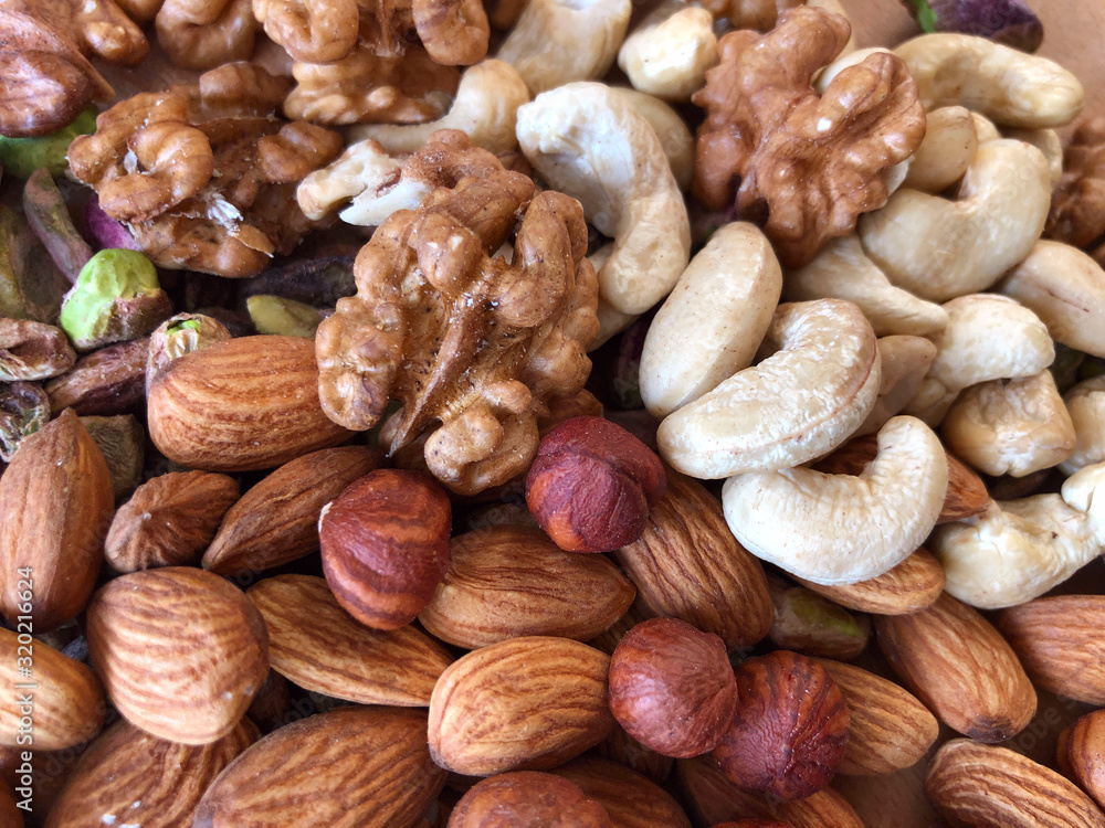 Food background. Top view on a mixture of different nuts. Peeled cashews, hazelnuts, pistachios, almonds and walnuts. The texture of dried nuts. Close-up, horizontal, top view. Healthy eating.