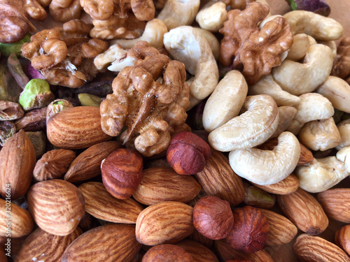 Food background. Top view on a mixture of different nuts. Peeled cashews, hazelnuts, pistachios, almonds and walnuts. The texture of dried nuts. Close-up, horizontal, top view. Healthy eating.