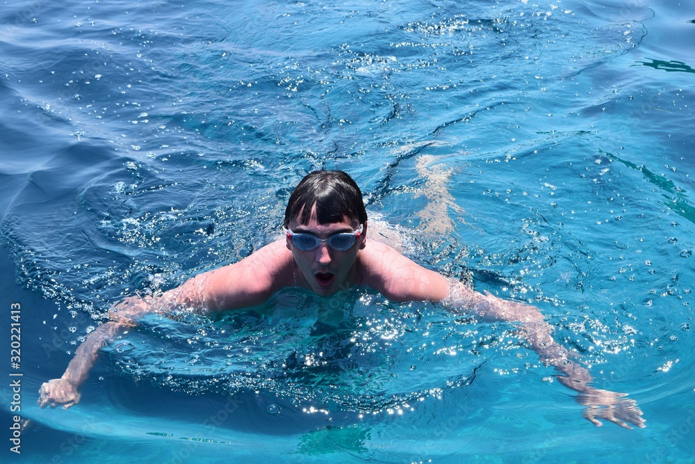 Fototapeta premium young man swimming in blue water portrait 