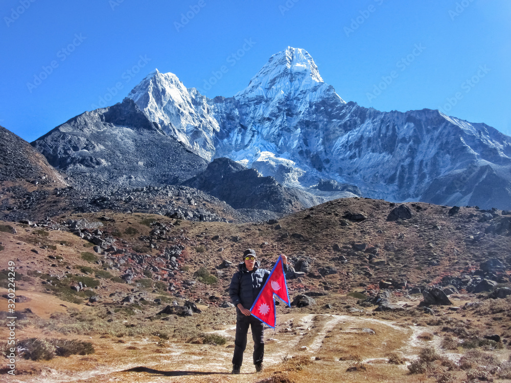 Guy holding National Flag of Nepal against Himalaya Mountain Peak. 