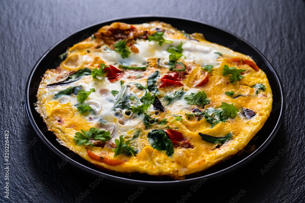 Breakfast - scrambled eggs with vegetables on black stone background Breakfast - scrambled eggs with vegetables on black stone background
