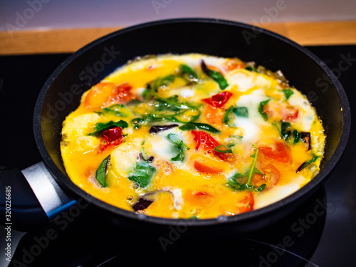 Breakfast - scrambled eggs with vegetables in frying pan