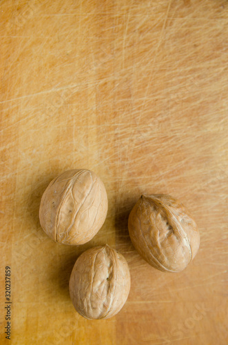 three walnuts on vintage wooden cutboard with knife marks. vertical view photo