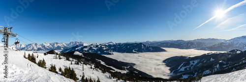 Panorama view of the Salzburg Alps from Schmittenhoehe, (Schmittenhohe) above Zell am See-Kaprun and Lake Zell, with blue sky cloud fog and snow mountain peaks on  winter sunny day, ski resort Austria photo