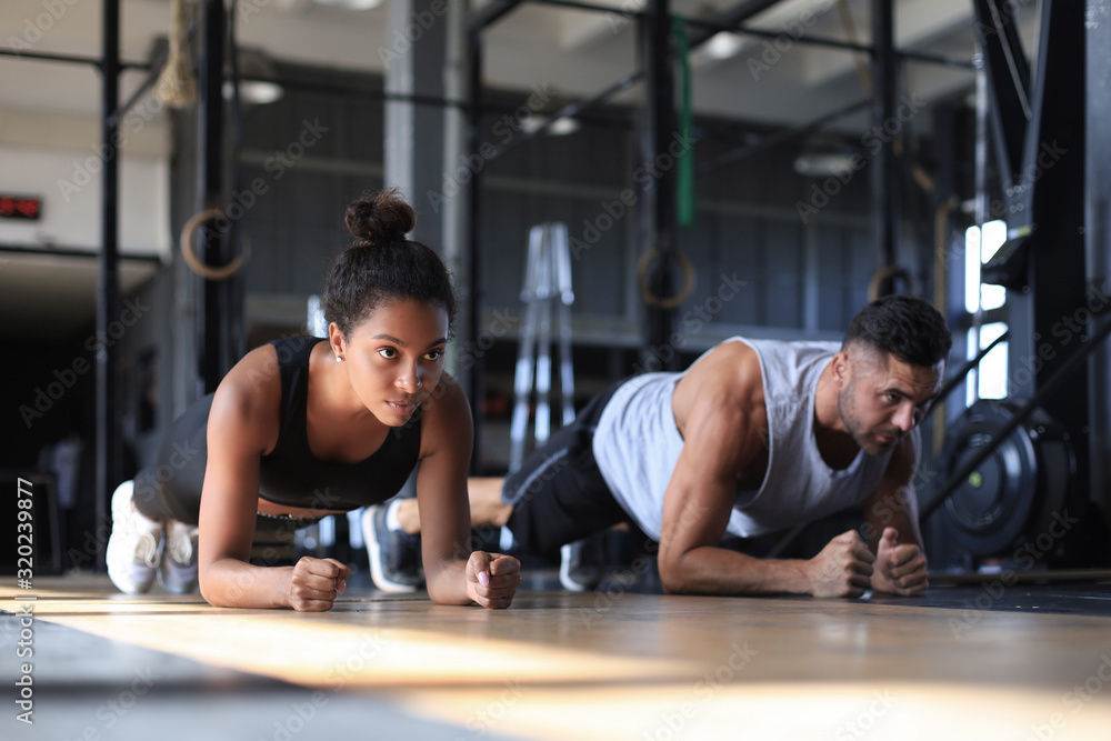Portrait of beautiful young sports couple on a plank position.