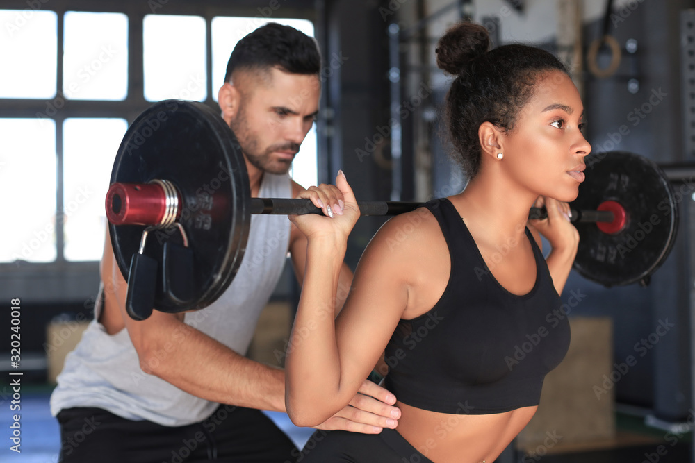 Man and woman with barbell flexing muscles in gym. Man and woman with barbell flexing muscles in gym.
