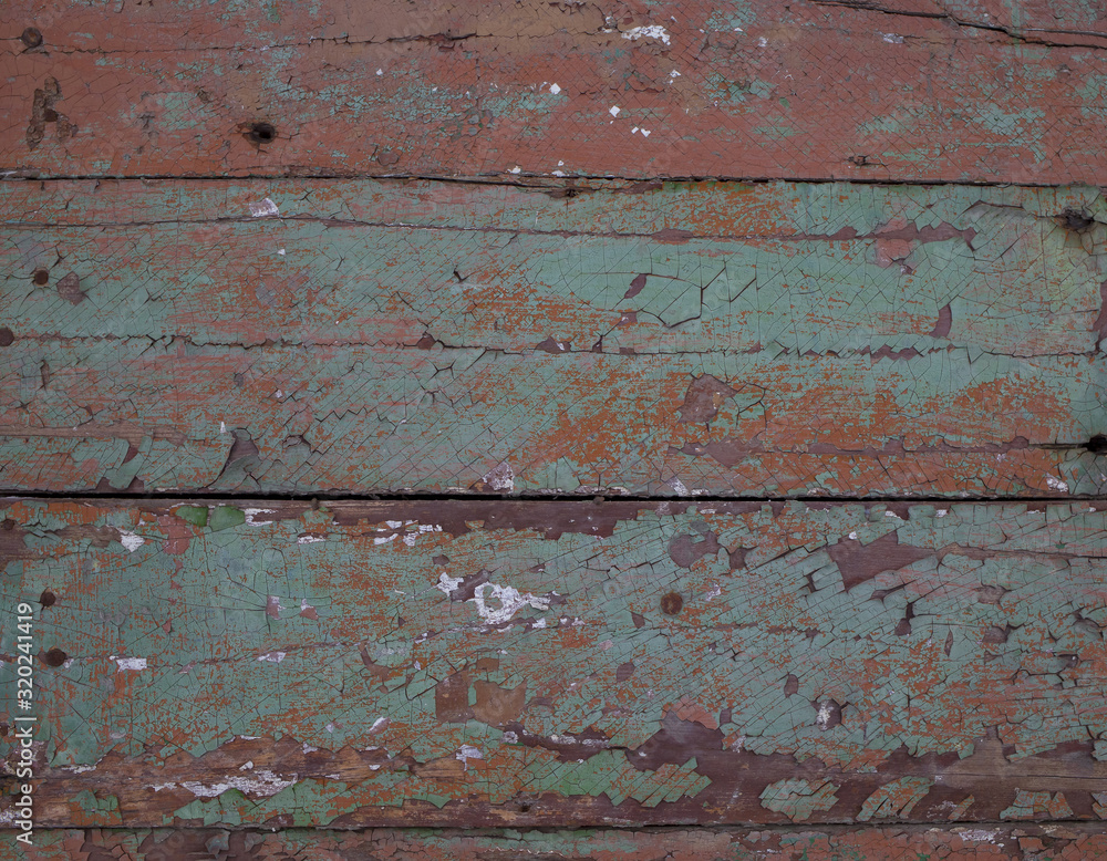 Texture. Fragment of an old wooden wall covered with cracked red, brown and green paint. Close-up.