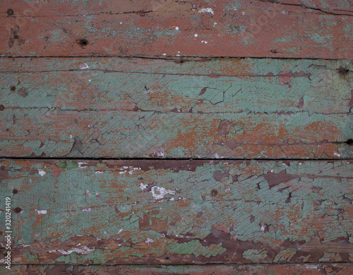 Texture. Fragment of an old wooden wall covered with cracked red, brown and green paint. Close-up.