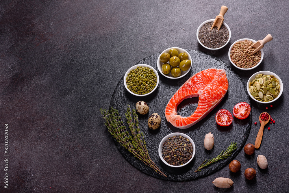 Raw trout red fish steak served with herbs and lemon and olive oil on a dark background Raw trout red fish steak served with herbs and lemon and olive oil on a dark background