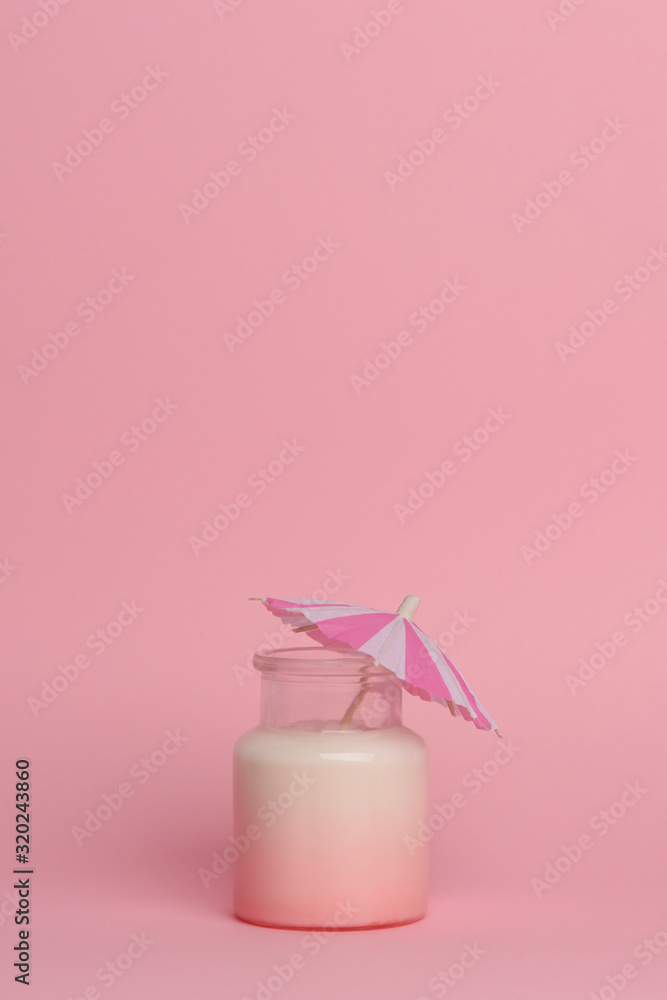 Milkshake with berry syrup in a glass jar mug isolated on a pink background. The jar is decorated with a cocktail paper striped umbrella. Place for text, copy space Milkshake with berry syrup in a glass jar mug isolated on a pink background. The jar is decorated with a cocktail paper striped umbrella. Place for text, copy space
