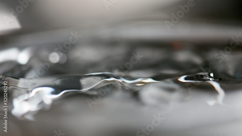 Abstract rippled background texture. Surface of water frozen in time, hi contrast lighting exposes the fascinating patterns created by soundwaves traveling directly through it. 