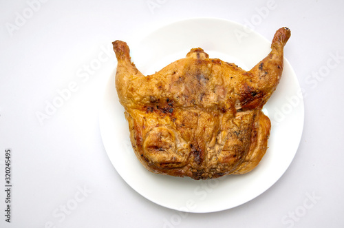 Tasty whole roasted chicken on white plate isolated on white
