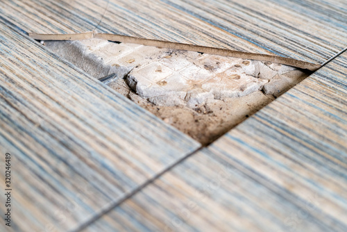 Close up view of broken tile in the bathroom. Cracked asbeston floor tile. Damaged ceramic tile background