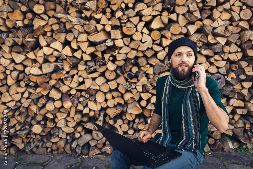 Fototapeta premium bearded businessman freelancer in headphones working on laptop and talking on phone
