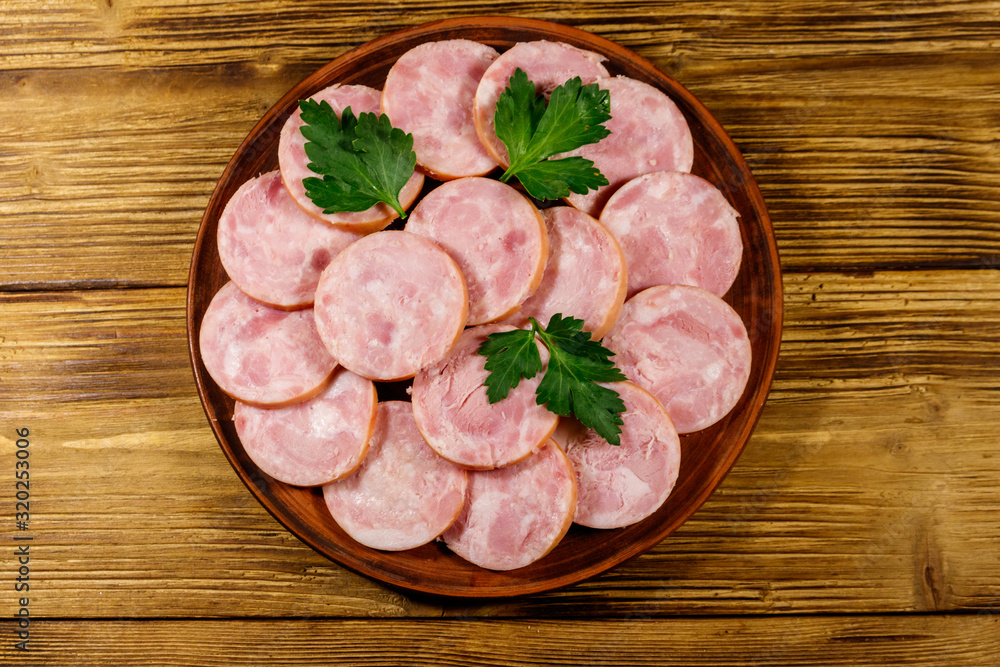 Ham sausage on a plate on wooden table. Top view Ham sausage on a plate on wooden table. Top view