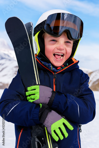 Happy little boy on a ski vacation in the mountains. Children's sports and ski training. Rest after skiing downhill.