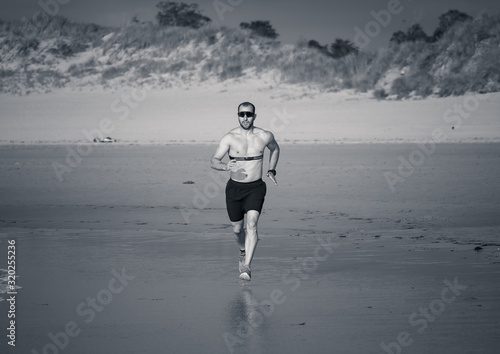 Fitness sports man using heart rate monitor running on beach