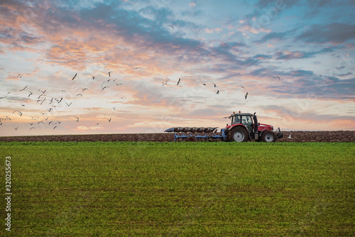 Fototapet farmer plowing his fields at sunset