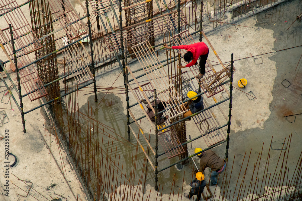 Construction workers in India climbing and building rebar platform at work site