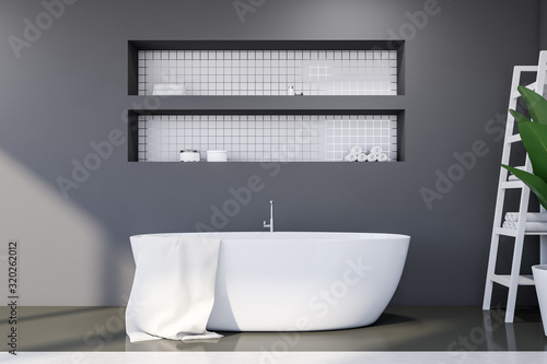 Gray and white tile bathroom with tub and shelves