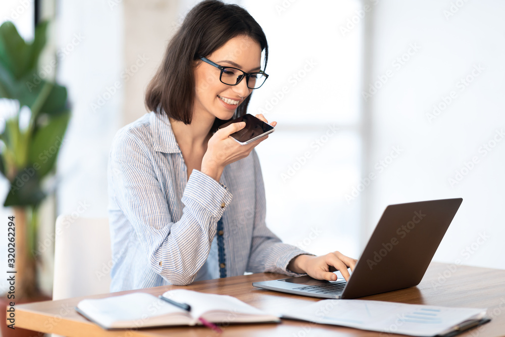 Woman using mobile voice recognition function and typing Woman using mobile voice recognition function and typing