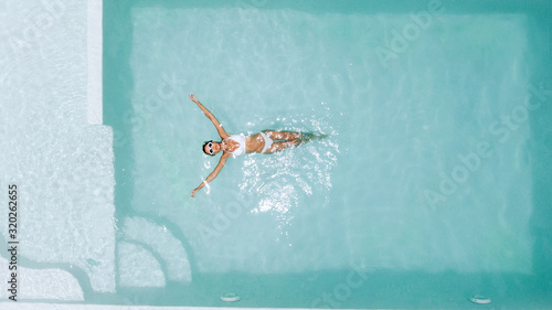 Fotografia Woman relaxing in clear pool water in hot sunny day on Bali villa