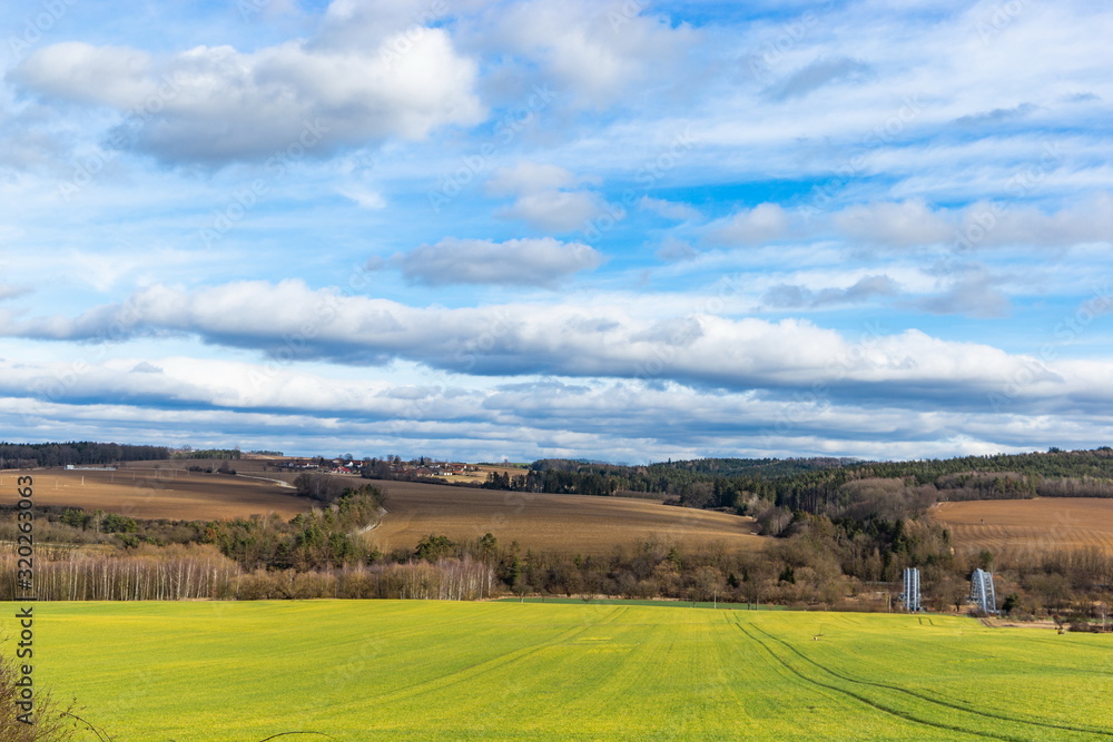 Early spring landscape in South Bohemia. Green field and forest. Blue sky.