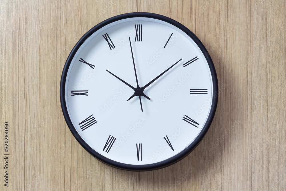 roman clock wall on woonden background. show time in late morning. black and white clock on timber panel for decoration in living room. roman clock wall on woonden background. show time in late morning. black and white clock on timber panel for decoration in living room.