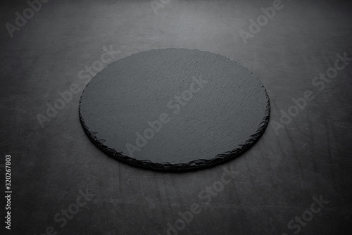 A round black slate dinner plate background material on a black background