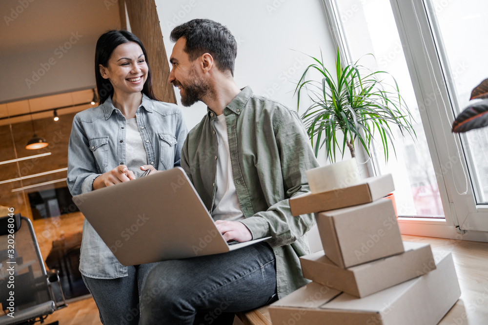 Communication of two colleagues in office. Young small business owners, selling online on a website. Online Sales, E-Commerce, Online Business, with postal parcel, selling online, delivery concept. Communication of two colleagues in office. Young small business owners, selling online on a website. Online Sales, E-Commerce, Online Business, with postal parcel, selling online, delivery concept.
