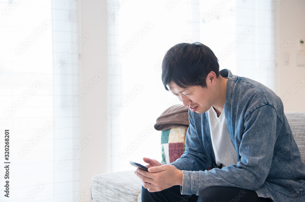 リビングでスマホをいじる男性 リビングでスマホをいじる男性