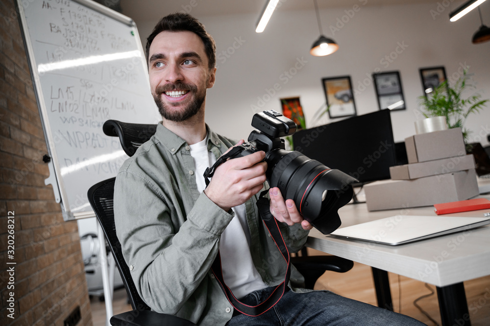 Smiled man holding camera and photographed goods. Young small business owner, selling online on a website. Online Sales, E-Commerce, Online Business, with postal parcel, selling online, delivery Smiled man holding camera and photographed goods. Young small business owner, selling online on a website. Online Sales, E-Commerce, Online Business, with postal parcel, selling online, delivery