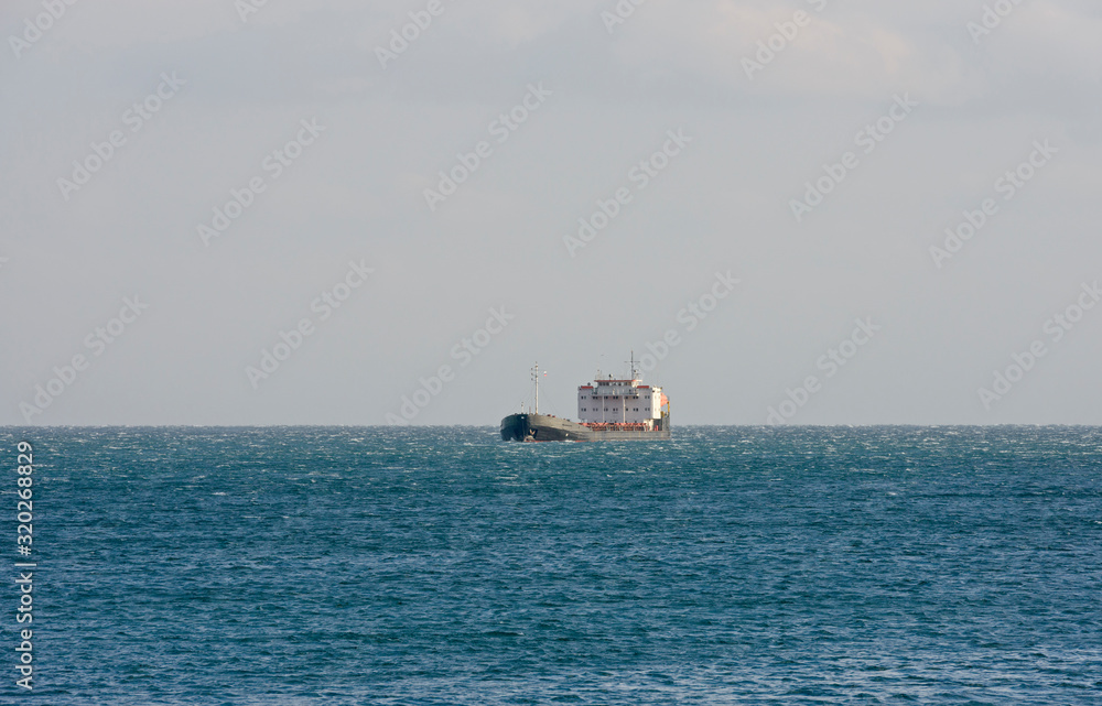 General cargo ship is in open sea in side sunlight.