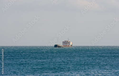 General cargo ship is in open sea in side sunlight. © vaz1