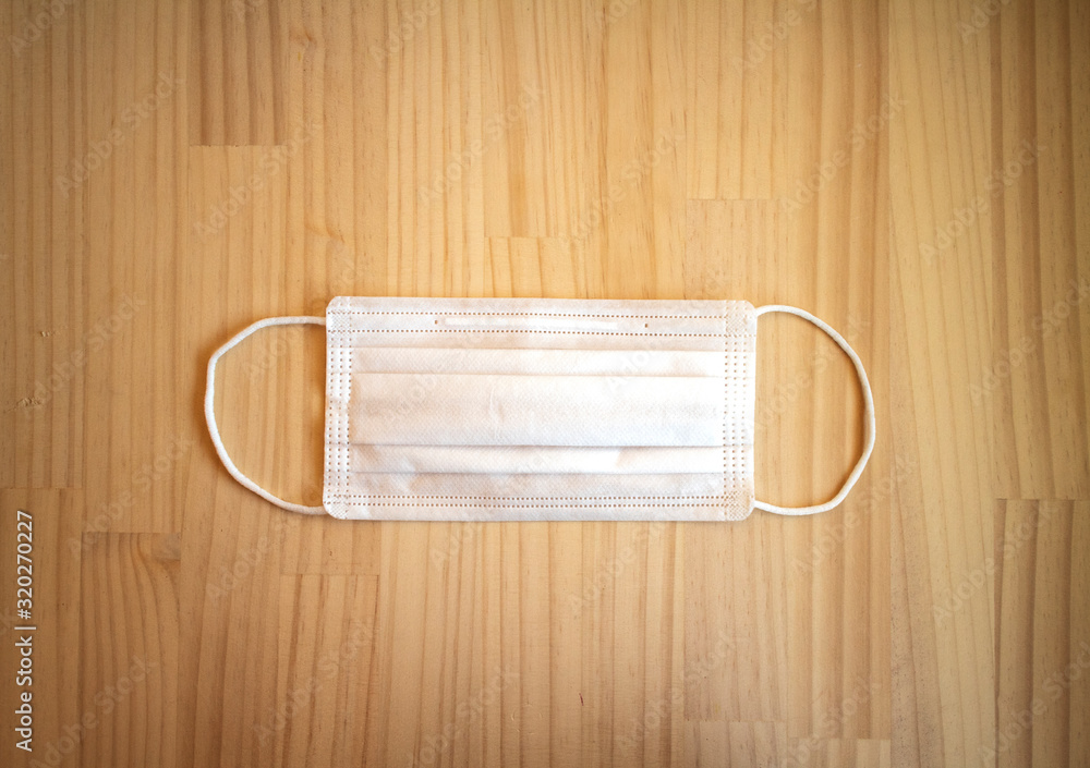 木製テーブルの上の白いマスク(正面、平置き) a white surgical mask on a wooden table 木製テーブルの上の白いマスク(正面、平置き) a white surgical mask on a wooden table