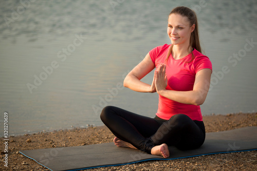 beautiful young woman in sportswear in summer yoga pose in a park near a lake © Alexandr