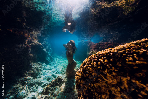 Woman in bikini posing underwater near corals in ocean. photo