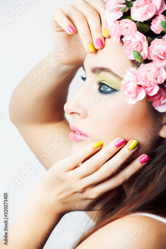 young pretty brunette woman with pink flowers and manicure posing cheerful isolated on white background closeup