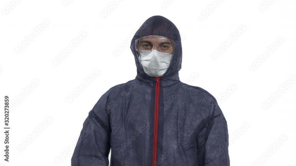Portrait of a caucasian man in protective suit, mask and glasses looking at camera. Making stop sign with his hand. Showing stop gesture. Studio, isolated on white background. Portrait of a caucasian man in protective suit, mask and glasses looking at camera. Making stop sign with his hand. Showing stop gesture. Studio, isolated on white background.