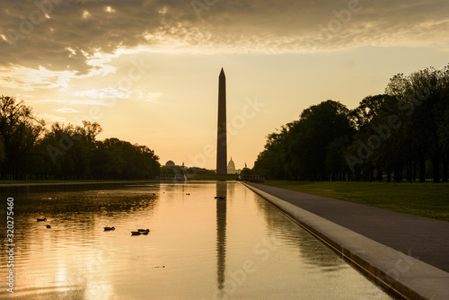 Washington Monument and Capitol Building view from Lincoln Memorial reflecting pool with ducks with dramatic cloud at sunrise